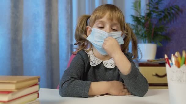 Trauriges Kindermädchen in medizinischer Maske beim Hausaufgabenmachen zu Hause, Videoanruf per Webcam im Internet — Stockvideo