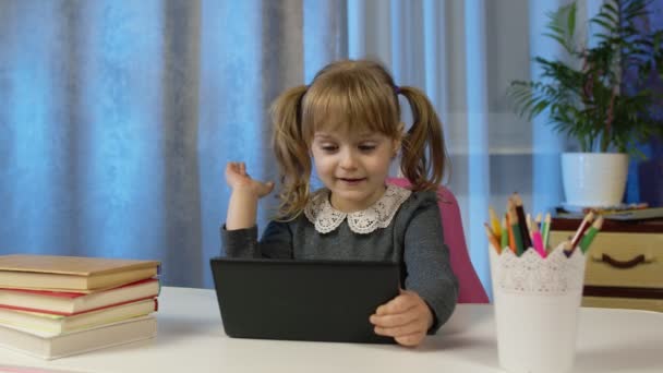 Дитя девочка школьница усваивает уроки с учителем находясь дома с помощью цифрового планшетного компьютера — стоковое видео