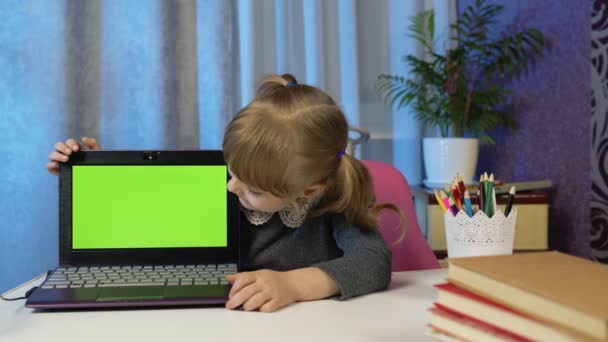 Niña estudiando e-learning, educación a distancia, niño apuntando a la pantalla verde portátil, croma key — Vídeo de stock