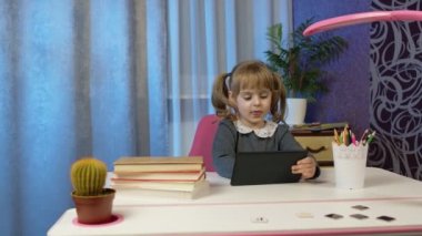 Çocuk okulu öğrenen kız, evde uzaktan eğitim laptopla masada oturuyor.