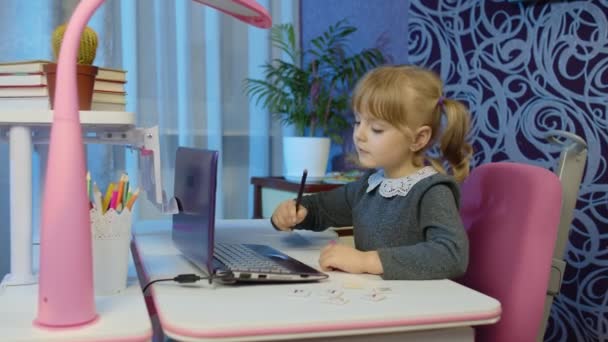 Evde dizüstü bilgisayar kullanarak okul ödevi yapan kız çocuğu, online çocuk uzaktan eğitim. — Stok video