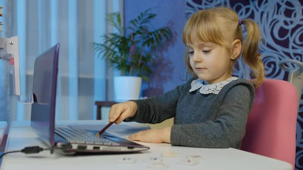 Учебные уроки для школьниц, дистанционное обучение дома, сидя за столом с ноутбуком — стоковое фото