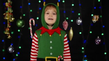 Noel Elf Noel Baba yardımcı kostümü giymiş kız el sallıyor. Merhaba, merhaba, selamlar.