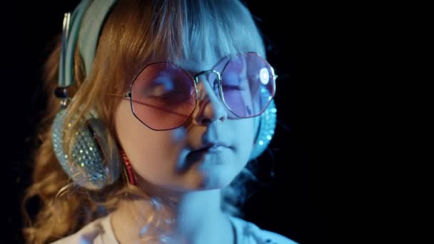 Стильный модный ребенок в солнечных очках на дискотеке киберпанк-клуба смотрит в камеру и улыбается — стоковое видео