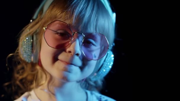 Porträt eines trendigen, stylischen Mädchens, das in die Kamera blickt, lächelnd, ein Kind im Neonlicht in einer Diskothek — Stockvideo