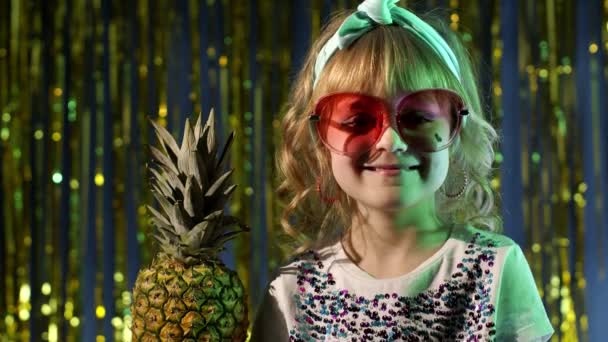 Modne stylowe dziecko z owocami ananasa picie soku w futurystycznym klubie z neonowym światłem — Wideo stockowe