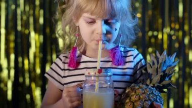 Ananas meyveli şık çocuk neon ışıklı fütüristik bir kulüpte meyve suyu içiyor.