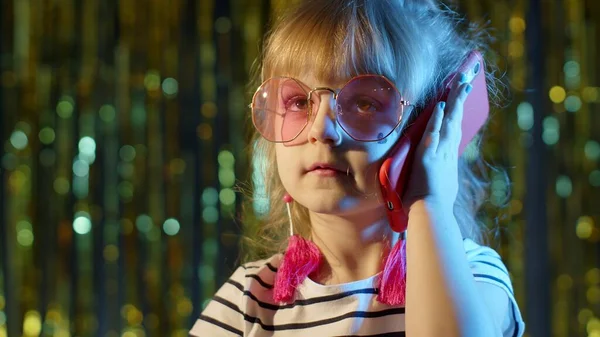 Flicka i futuristiska glasögon talar på mobiltelefon med vän i nattklubb med neon blått ljus — Stockfoto
