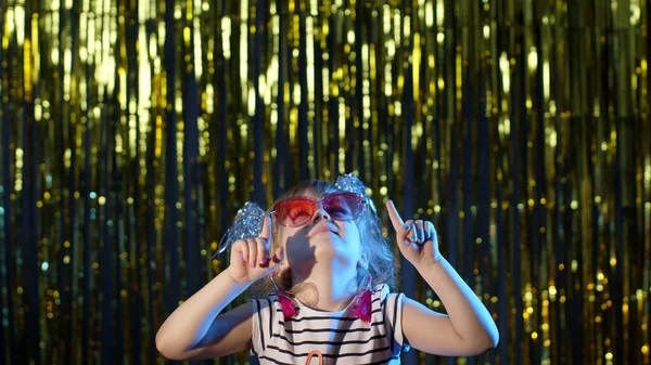 Elegante adolescente niña de pie en luces de neón azul retroiluminado y puntos en el espacio en blanco, signo de acuerdo — Foto de Stock