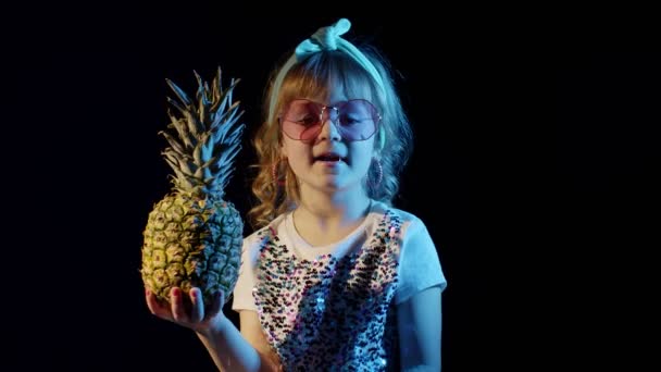 Snygg tonåring kaukasiska unge flicka med ananas står på svart bakgrund sång, lura runt — Stockvideo