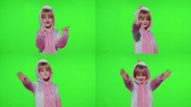 Küçük kız gülümsüyor, el sallıyor, selamlıyor, merhaba ya da güle güle, elinde tek boynuzlu at pijamalarıyla kroma anahtarıyla.