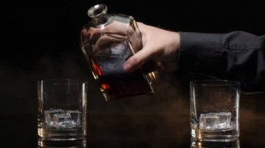 Barmen, şişeden bardaklara altın viski konyağı dök. Koyu arkaplanda buz küpleri olsun.