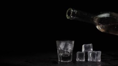 Barmen elinde votka, tekila ya da buzlu siyah arka planda şişeden cama sake doldurur.