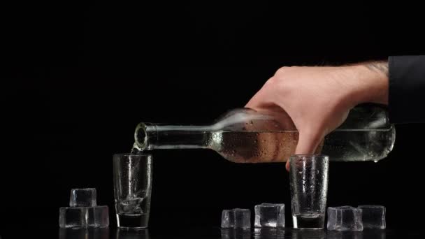 Две руки с бокалами водки, чтобы поднять тост на черном фоне с кубиками льда — стоковое видео