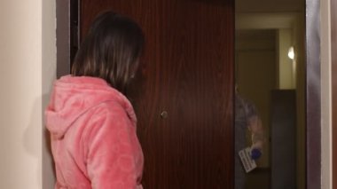 Yazılı metni olan doktor, Coronavirus 'a karşı aşı önererek evdeki kadını ziyaret ediyor.