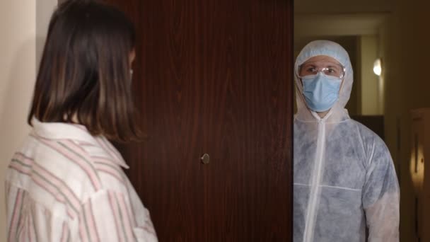 Orvosi dolgozó szöveggel, papíron látogató nő otthon kínál oltást a koronavírus ellen — Stock videók