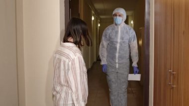 Aşısı olan bir tıp çalışanı, Coronavirus salgınına karşı aşı önererek eve gelen bir kadını ziyaret ediyor.