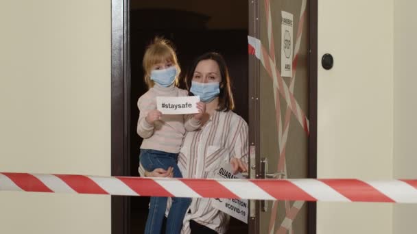 Sjuk mor med dotter i medicinska masker som öppnar dörren, karantänavstängning av coronavirus — Stockvideo