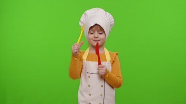 Aşçı kız çatal ve bıçakla yemek pişiriyor. Krom anahtar arka planında kafa sallıyor.
