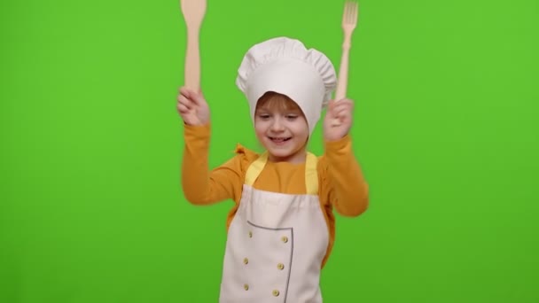 Niño divertido niña vestida cocinero panadero en delantal y sombrero bailando, tonteando, haciendo caras — Vídeo de stock