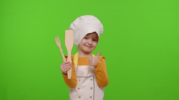 Dziecko dziewczyna gotować kucharz piekarz w fartuchu i kapelusz uśmiechnięty, kiwa głową w porozumieniu na tle klucza chroma — Wideo stockowe