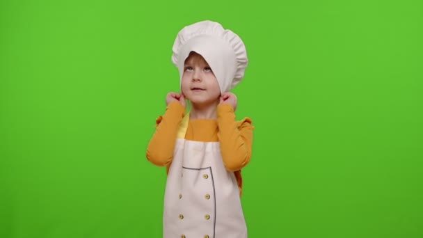 Gyermek lány gyerek öltözött professzionális szakács mosolyog, keresztbe karok és néz intenzíven a kamera — Stock videók