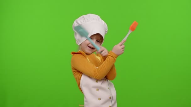 Grappig kind meisje kind gekleed kok chef-kok bakker in schort en hoed dansen, rotzooien rond, het maken van gezichten — Stockvideo
