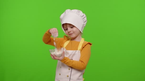子供の女の子の服を着た料理人のパン屋でエプロンと帽子プレート内の小麦粉を攪拌,周りを欺く — ストック動画