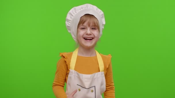 Urocze dziecko dziewczyna ubrana jak kucharz śmieje się głośno po usłyszeniu absurdalnej anegdoty — Wideo stockowe