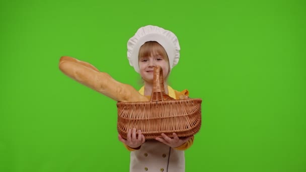 Enfant fille habillé en cuisinier professionnel chef souriant et montrant panier avec baguette et pain — Video