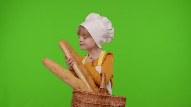 Kindermädchen als Kochprofi verkleidet lächelt und zeigt Korb mit Baguette und Brot — Stockvideo