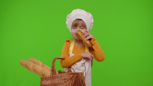 Kinderköchin zeigt Korb mit Baguette und Brot, lächelt, schnuppert, isst Brötchen mit Sahne — Stockvideo