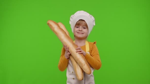 Enfant fille enfant cuisinier chef boulanger renifler deux baguettes fraîches, souriant, agitant la tête en accord — Video