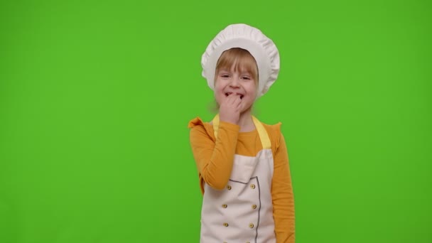 Gyermek lány köténybe öltözött, mint a szakács szakács eszik finom friss epret, és nevetve hangosan — Stock videók