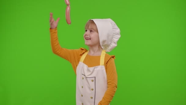 Dziecko dziewczynka dzieciak przebrany za kucharza biorąc kiełbaski z góry, wygłupiając się, co twarze — Wideo stockowe