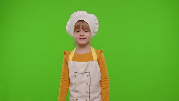 Ребенок девочка повар пекарь позируя, улыбаясь, показывая большой палец вверх на зеленом фоне хромы ключ — стоковое видео