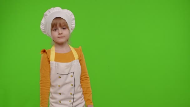 Dziewczyna dzieciak przebrany za kucharza piekarz pozowanie, uśmiech, patrząc na aparat fotograficzny na tle klawisza chroma — Wideo stockowe