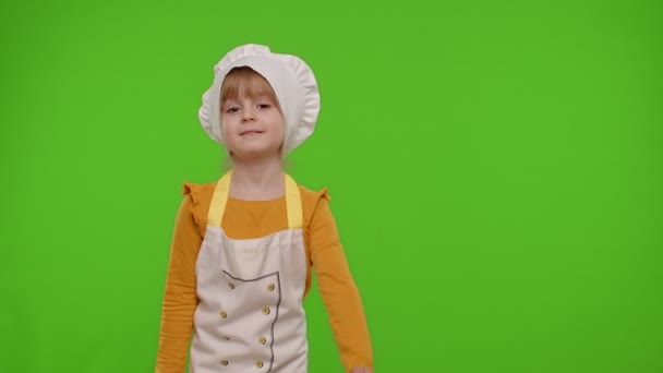 Niña vestida como chef cocinero apuntando a la derecha en el espacio en blanco lugar para su logotipo de anuncio — Vídeos de Stock