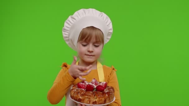 Dziecko dziewczyna dzieciak przebrany za profesjonalnego kucharza piekarz jedzenie smaczne ciasto truskawkowe na klucz chroma — Wideo stockowe