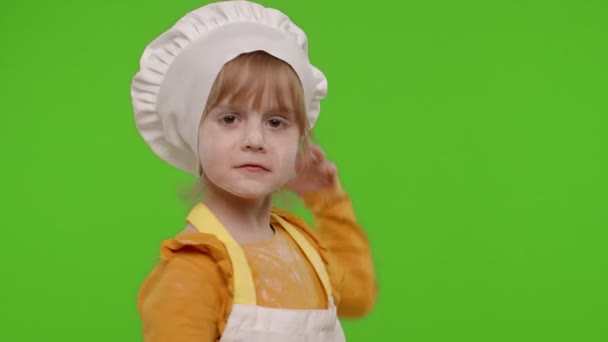 Смішна дитина дівчинка, одягнена кухаря пекарні в фартух і капелюсі танцює, обдурює, робить обличчя — стокове відео