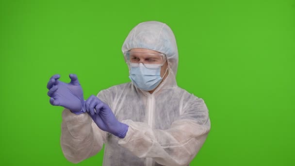 クロマキーに立つ医療従事者の医師と手袋やマスク、コロナウイルスのパンデミックを置きます — ストック動画