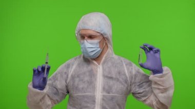 Aşı ampullü PPE giysisi giyen doktor ellerinde Coronavirus 'a karşı aşı öneriyor.