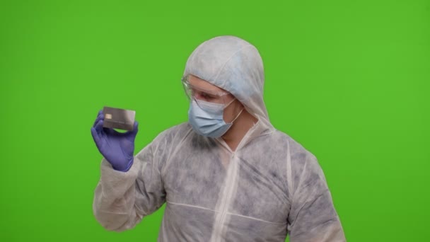 Γιατρός με κοστούμι PPE με αμπούλα εμβολίου coronavirus και πιστωτική κάρτα στα χέρια σε πράσινο κλειδί chroma — Αρχείο Βίντεο