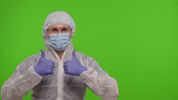 Medico in tuta protettiva PPE che punta a destra sullo spazio vuoto su sfondo cromatico chiave — Video Stock
