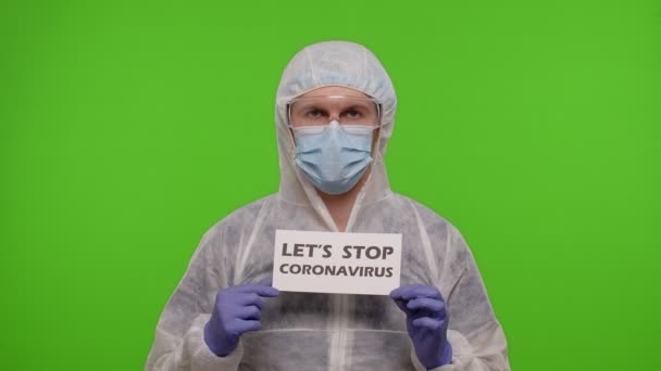 Portret lekarza w garniturze PPE z hasłem tekstowym na papierze Pozwala zatrzymać koronawirusa — Wideo stockowe