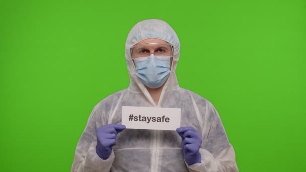 Retrato del médico en traje de PPE con eslogan de inscripción de texto sobre papel Stay Safe en croma key — Vídeo de stock