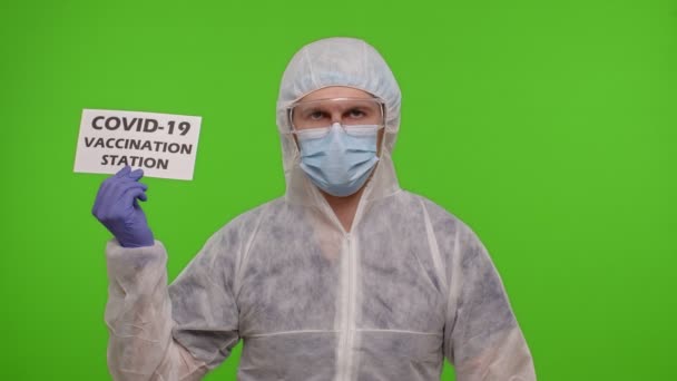 Médico em terno PPE com ampola de medicamento e texto em papel - Estação de Vacinação Covid-19 — Vídeo de Stock