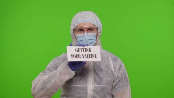 Lékařský pracovník v obleku PPE s injekční stříkačkou, ampulkou, textovým sloganem na papíře — Stock video