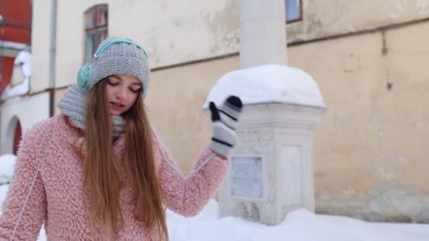 Chica turística durante sus vacaciones escuchando música a través de auriculares y bailando en el centro de la ciudad vieja — Vídeos de Stock