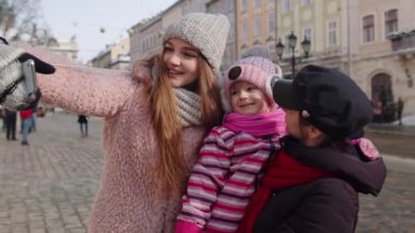 Kız kardeş turistler selfie çekiyorlar, poz veriyorlar, cep telefonlarıyla konferans yapıyorlar.